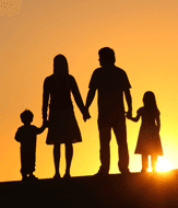A family of four silhouetted against an orange sunset